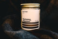 Candle jar labeled 'Autumn Flannel' by Pipe Dream Candle Studio on a flannel background.