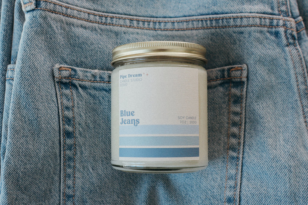 Candle labeled 'Blue Jeans' in a pocket of blue denim jeans