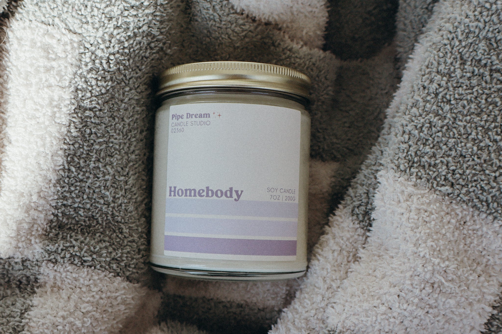 Candle labeled 'Homebody' on a textured blanket