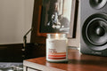 A lit jar candle labeled 'Perfect Fall Day' sits on a record player stand next to a black speaker, with a Carole King's vinyl album Tapestry visible in the background.