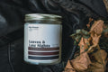 Candle jar labeled 'Leaves & Late Nights' lain on a leather jacket  with leaves.