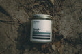 Candle labeled 'Spooky Beach' on a sandy beach with leaves